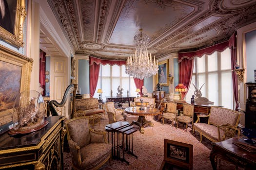 Salon élégant du Château de Sainte-Julie, décoré de meubles anciens, d'un lustre et de tableaux classiques.