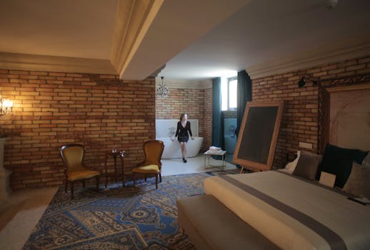 Chambre spacieuse avec murs en briques, lit confortable, coin salon et baignoire, ambiance élégante et chaleureuse.