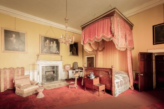 Chambre élégante du Château de Sainte-Julie avec lit à baldaquin, cheminée et décorations historiques.