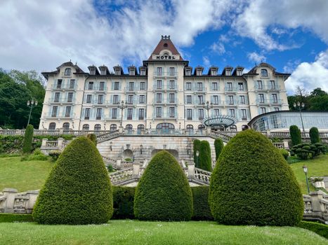 Hôtel élégant avec jardin paysager et nuages dans le ciel, situé près d'un château en région.