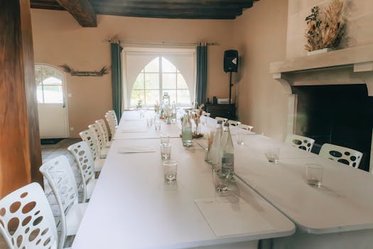 Salle de séminaire au Château de Sainte-Julie, avec une grande table, chaises blanches et décor chaleureux.