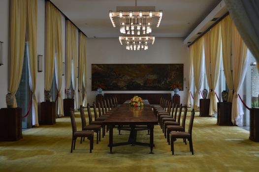 Salle de séminaire au Château de Sainte-Julie avec une grande table en bois et des chaises, éclairée par un lustre moderne.