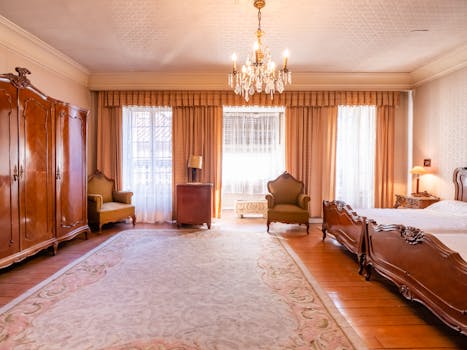 Chambre élégante au Château de Sainte-Julie avec un lit, un mobilier en bois et des rideaux drapés.